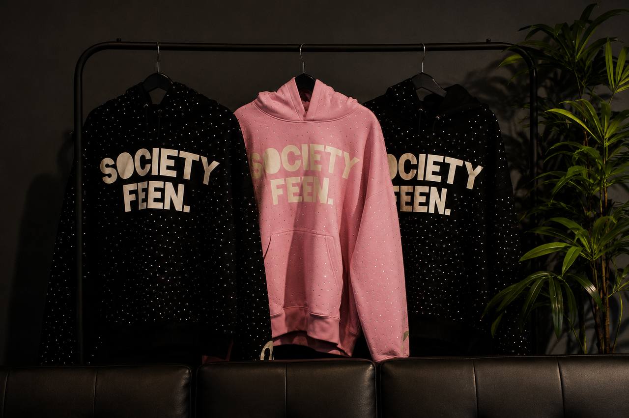 Existing Society Feen website artwork showing pink and black hoodies on a clothing rack.